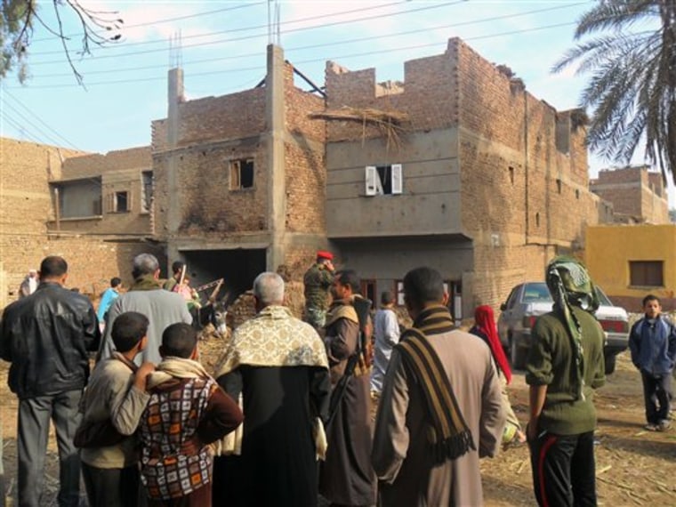 Security forces and bystanders stand outside a damaged house following clashes in Assuit, Egypt, on Saturday.